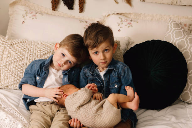 kleine jungen mit ihrem neugeborenen kleinen bruder - furniture barefoot little boys family stock-fotos und bilder