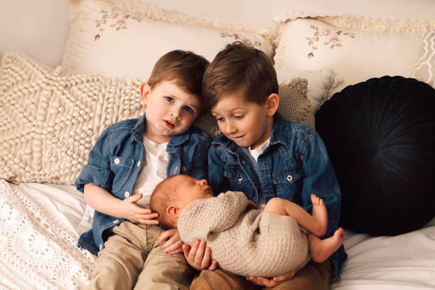 kleine jungen mit ihrem neugeborenen kleinen bruder - furniture barefoot little boys family stock-fotos und bilder