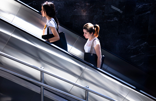 Belgrade, Serbia - June 15, 2022: Two women going up on subway escalator , on a sunny day