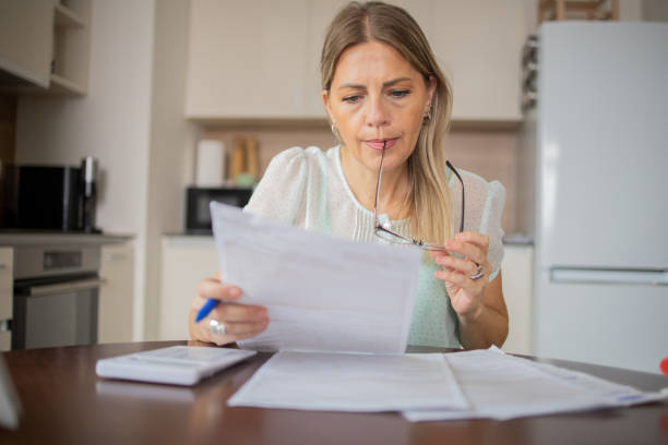 istock Mature woman using calculator while going through bills and home finances 1506254745