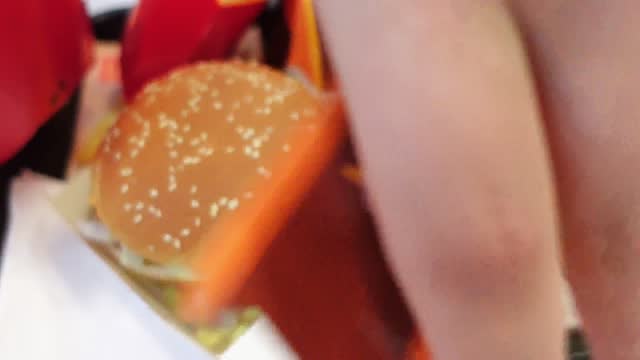 McDonald's food tray. Hand opens Big Mac, pours french fries into box. Fast food
