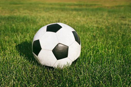 Classic soccer ball, typical black and white pattern, placed on the spot of the stadium turf. Traditional football ball on the green grass field of arena.