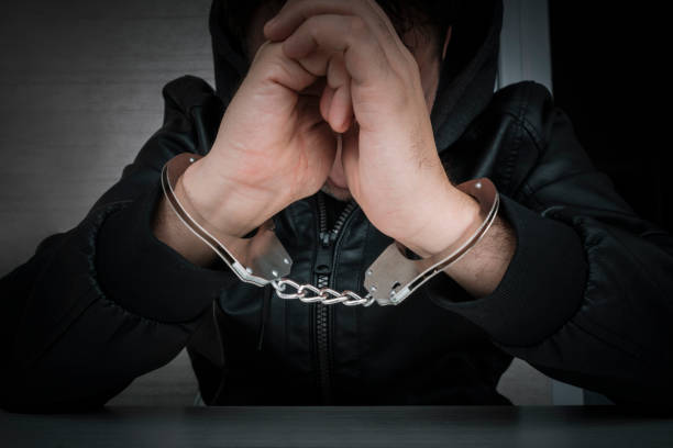 a dangerous criminal is handcuffed in prison for interrogation. A repentant sad man with his head on the table. Arrest of a bandit.