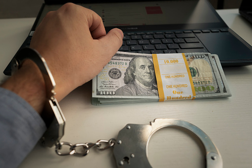 male Hands in handcuffs with money. Cyber Crime Concept