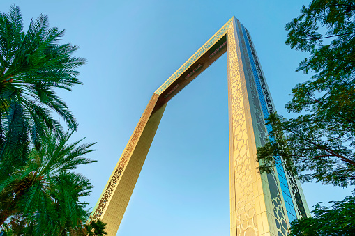 Dubai, UAE. November 25, 2022: Dubai Golden Frame best new landmark, which located in Zabeel Park. View on golden frame and palm tree