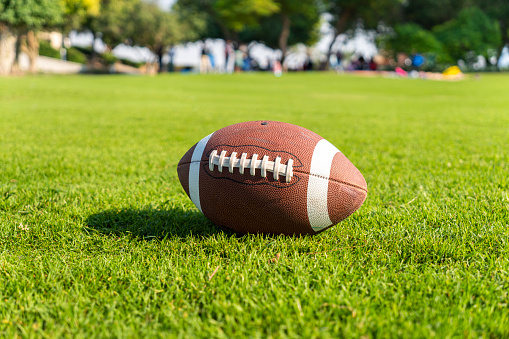 ball for American football on a grass field. Close up view with out of focus background.