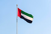 UAE flag waving in the blue bright sky, national symbol UAE