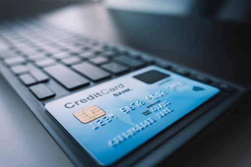 payment by credit card via the Internet. A blue plastic bank card is lying on a black laptop keyboard. nfc card payment reading