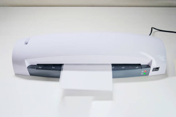 una máquina para laminar fotos y documentos con plástico. laminador blanco de escritorio, primer plano - laminated plastic printout paper industry fotografías e imágenes de stock