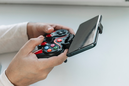 man hands with game controller connected with smartphone. Electronic devices and technology concept