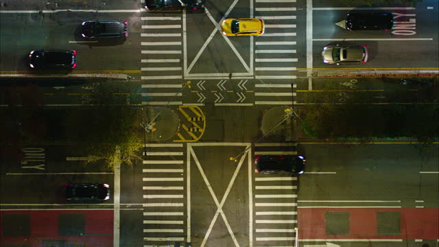 Looking down, directly-above view on the pedestrian crossing on the busy Delancey Street, Manhattan, New York, in the night. Aerial clip with the rock-solid static camera.