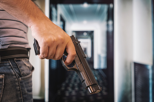 bank robbery. an armed criminal with a dhrt pistol enters the premises. Attempted robbery. Crime concept. self-defense with firearms. the man hides the gun behind his back.