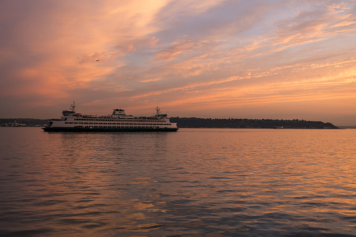 Seattle, USA - Aug 19, 2022: Sunset over Elliott Bay on the waterfront as a Washington State Ferry Passes.