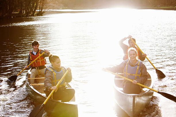 amici di canottaggio canoa sul lago ancora - men sitting canoe canoeing foto e immagini stock