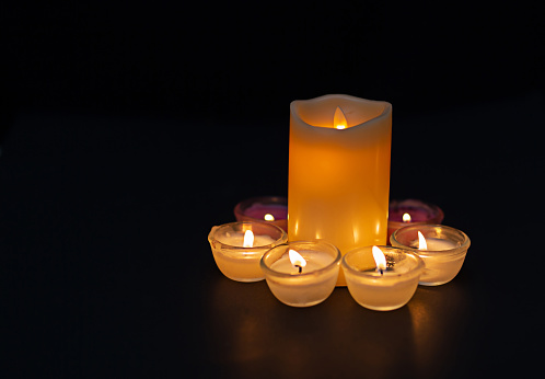 Candle lighting. Shallow depth of field. Numerous Christmas candles light up at night. abstract candle background Numerous candle flames shine on a dark background. Close-up. Empty space.