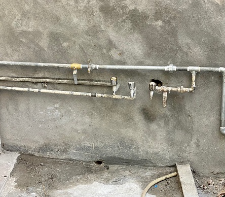 Water pipe wiring and taps along side the cement wall at a construction site