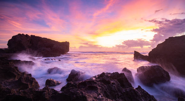 A magical pink and purple rocky ocean sunset in Okinawa stock photo