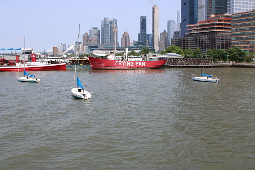 New York, NY, USA-June 19, 2023: Iconic Frying Pan boat restaurant and sailboats, on Hudson River, with Manhattan skyline in the background