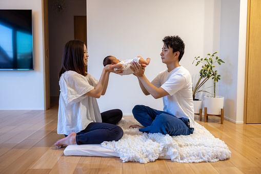 Mother and father holding newborn baby in living room
