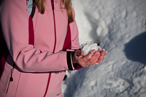 Midsection of woman holding snowball in her hands, Austria