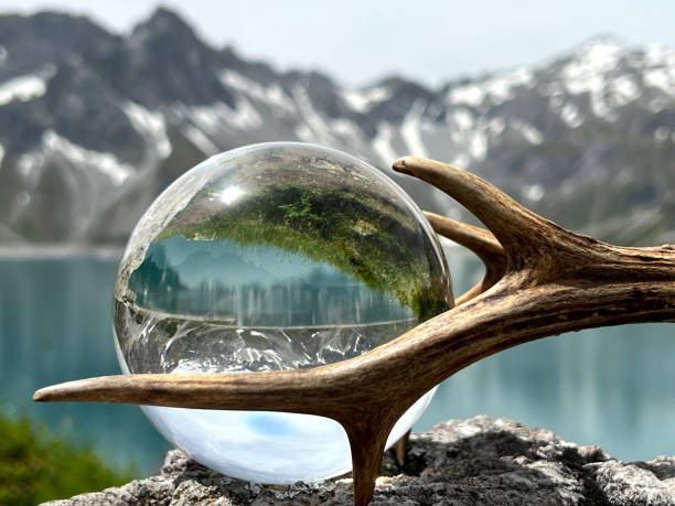 Roebuck antlers next to lensball, crystal ball, with reflections of Lake Lunersee (Lünersee, Montafon, Vorarlberg). stock photo