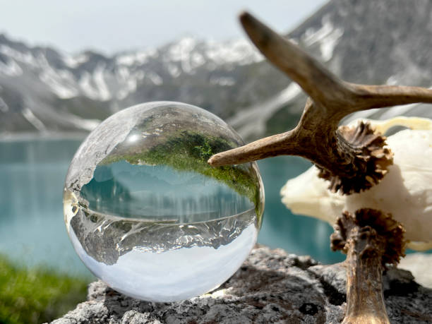 Roebuck antlers next to lensball, crystal ball, with reflections of Lake Lunersee (Lünersee, Montafon, Vorarlberg). stock photo