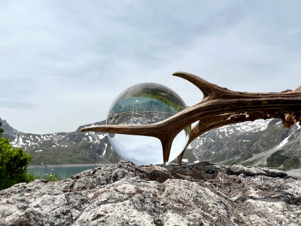 Roebuck antlers next to lensball, crystal ball, with reflections of Lake Lunersee (Lünersee, Montafon, Vorarlberg). stock photo