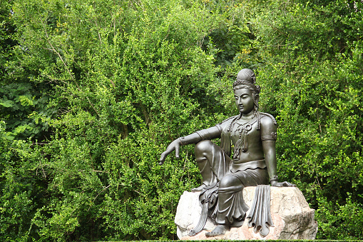 Buddha figure sitting on a rock in front of mountains and the mediterranean sea on Majorca. Part of a series.