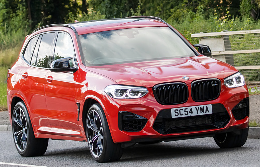 Milton Keynes,UK - June 24th 2023. 20 red BMW X3 M COMPETITION AUTO car travelling on an English country road