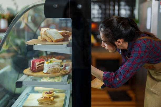 istock Cafe worker is opening bakery cabinet, bent down use tongs pick cake in refrigerator out put them on sall tray, that is served customers who order eat in store, when finished, close cabinet as before. 1506561114
