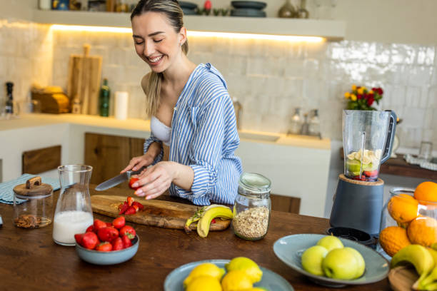 istock Happy woman slicing fruit while preparing smoothie in the kitchen 1506561871