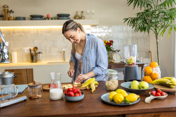 istock Happy woman slicing fruit while preparing smoothie in the kitchen 1506566750