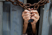 woman trapped in an illegal cargo container locked with chains and keys. Has the idea of trying to escape and seeking freedom from the outside : Concept of human trafficking