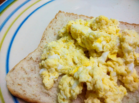 Penang, Malaysia \nPhotos of my scrambled eggs on a slice of bread. Some have a cup of instant coffee by its side. Also, some have ketchup on the eggs. Vignette applied.