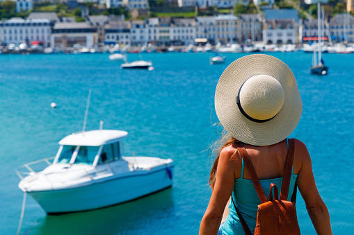 beautiful tourist woman with sunhat looks at turquoise sea and boat- vacation,  travel destination,  relax concept