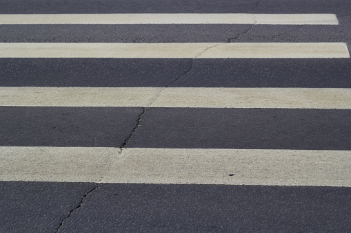 Photo of footpath white stripes on gray asphalt. Road traffic. Road coverage.