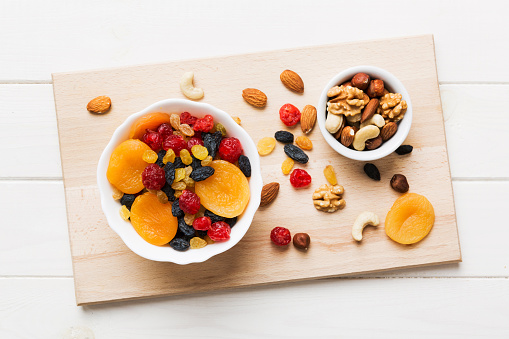 healthy snack: mixed nuts and dried fruits in bowl on table background, almond, pineapple, cranberry, cherry, apricot, cashew.