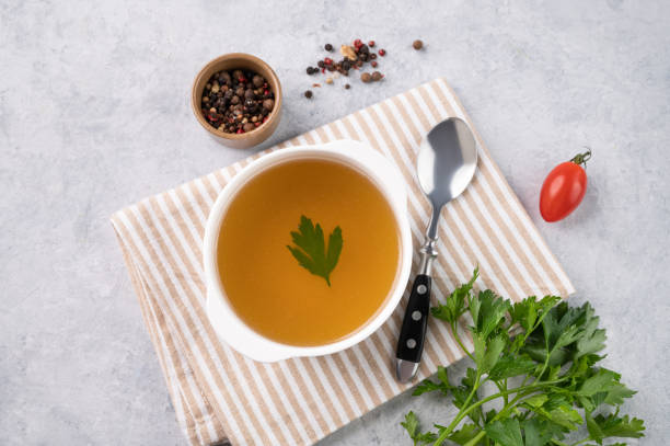 istock Meat broth with parsley in a white plate on a light background with fresh herb, spoon and napkin. The concept of healthy diet food. 1506718020