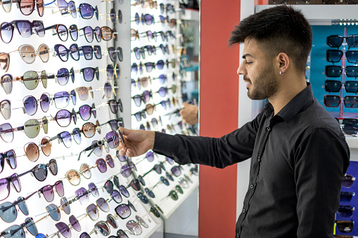 Young man trying on sunglasses in optical shop