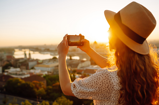 Tourist woman shoots a city landscape at dawn on a smartphone.