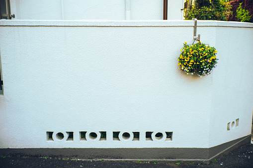 A round planter displayed on a white wall of a house in downtown Tokyo.