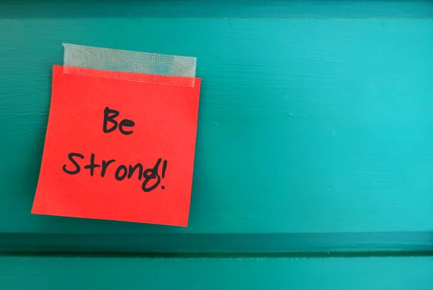 istock red note on copy space green wall with text handwritten BE STRONG , concept of self reminder to keep trying ,never give up and be persistent. 1506838541
