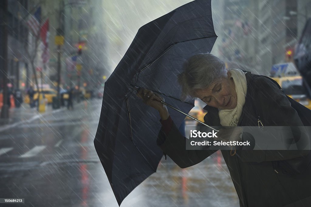 Matura donna con ombrello contro il vento - Foto stock royalty-free di Pioggia