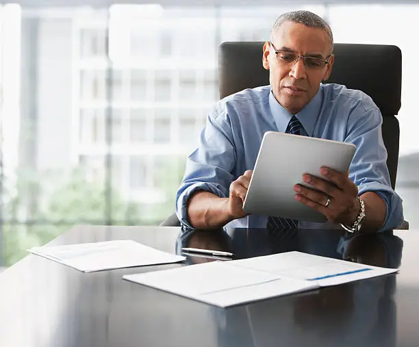 Photo of Businessman looking over electronic tablet