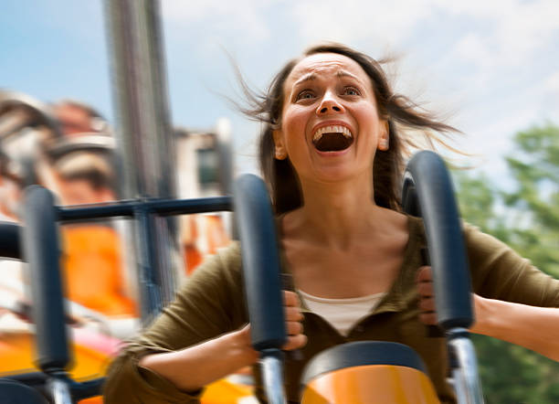 young woman screaming on a rollercoaster - lunapark treni stok fotoğraflar ve resimler