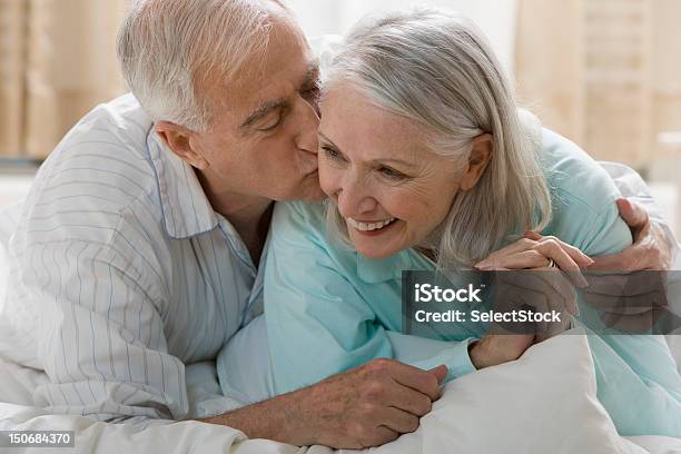 Photo libre de droit de Senior Homme Embrasser Femme Au Lit banque d'images et plus d'images libres de droit de 65-69 ans - 65-69 ans, Adulte, Affectueux