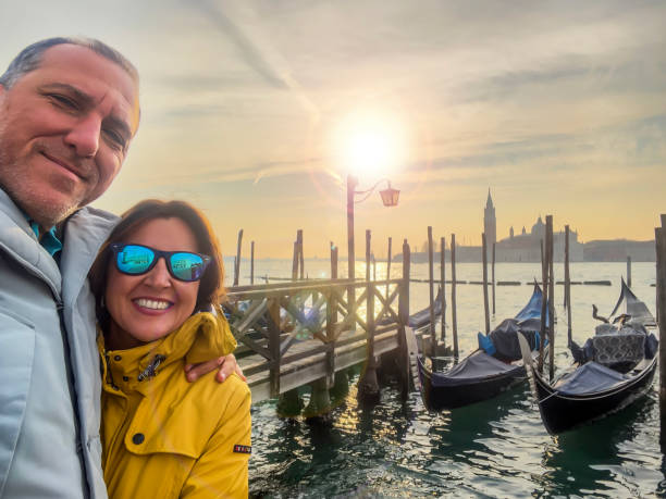 Hugging couple taking selfie in Venice Very handsome mid adult hetersexual man and beautiful woman smiling and looking at camera. Happy real people. Travel destination background, copy space. Honeymoon just married husband and wife posing at the grand canal venice italy grand canal honeymoon gondola stock pictures, royalty-free photos & images