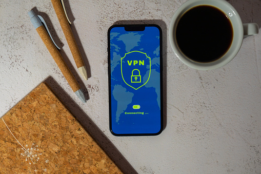 Mobile phone App screen of VPN creation Internet protocols for protection private network Virtual private network anonymous safe and secure internet access on smartphone on workplace background with coffee pen and notebook. Future technologies