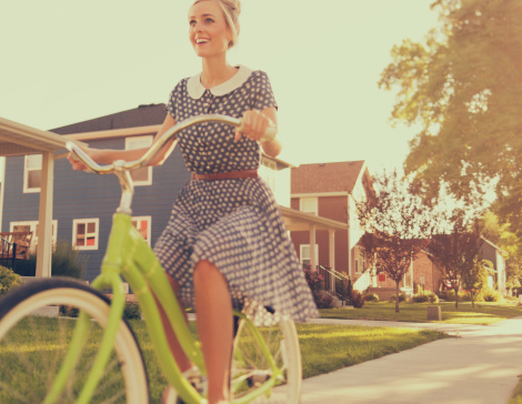 A retro female enjoys a ride on her vintage bike in the summer afternoon.