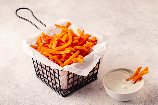 Sweet potato fries in a basket with blue cheese sauce.